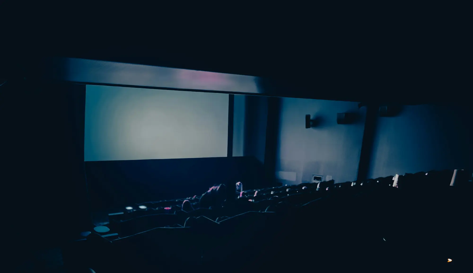 An empty cinema auditorium with the screen lit.
