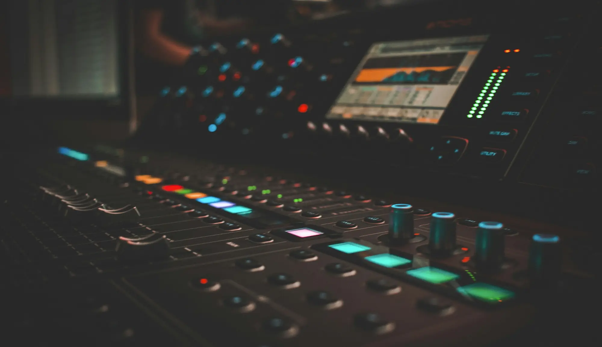 A lit mixing console in a dark control room.