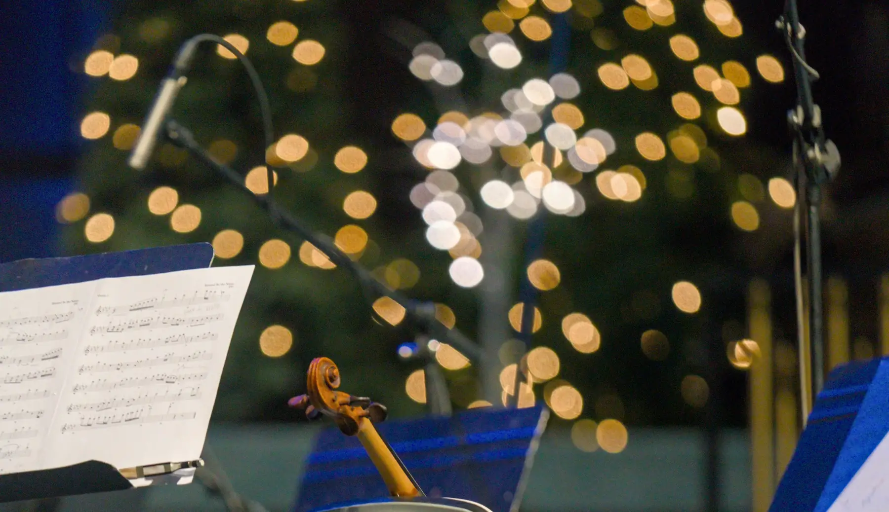 A violin and a music stand on a lit stage.